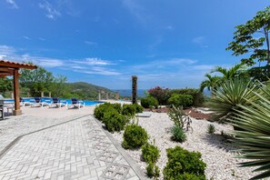 A pool area with lounge chairs, a pergola, and a view of the sea. - Casa Antonelli (Sardinal)