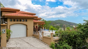 A residential building with a large garage, a covered porch, and a view of a hilly landscape. - Casa Antonelli (Sardinal)