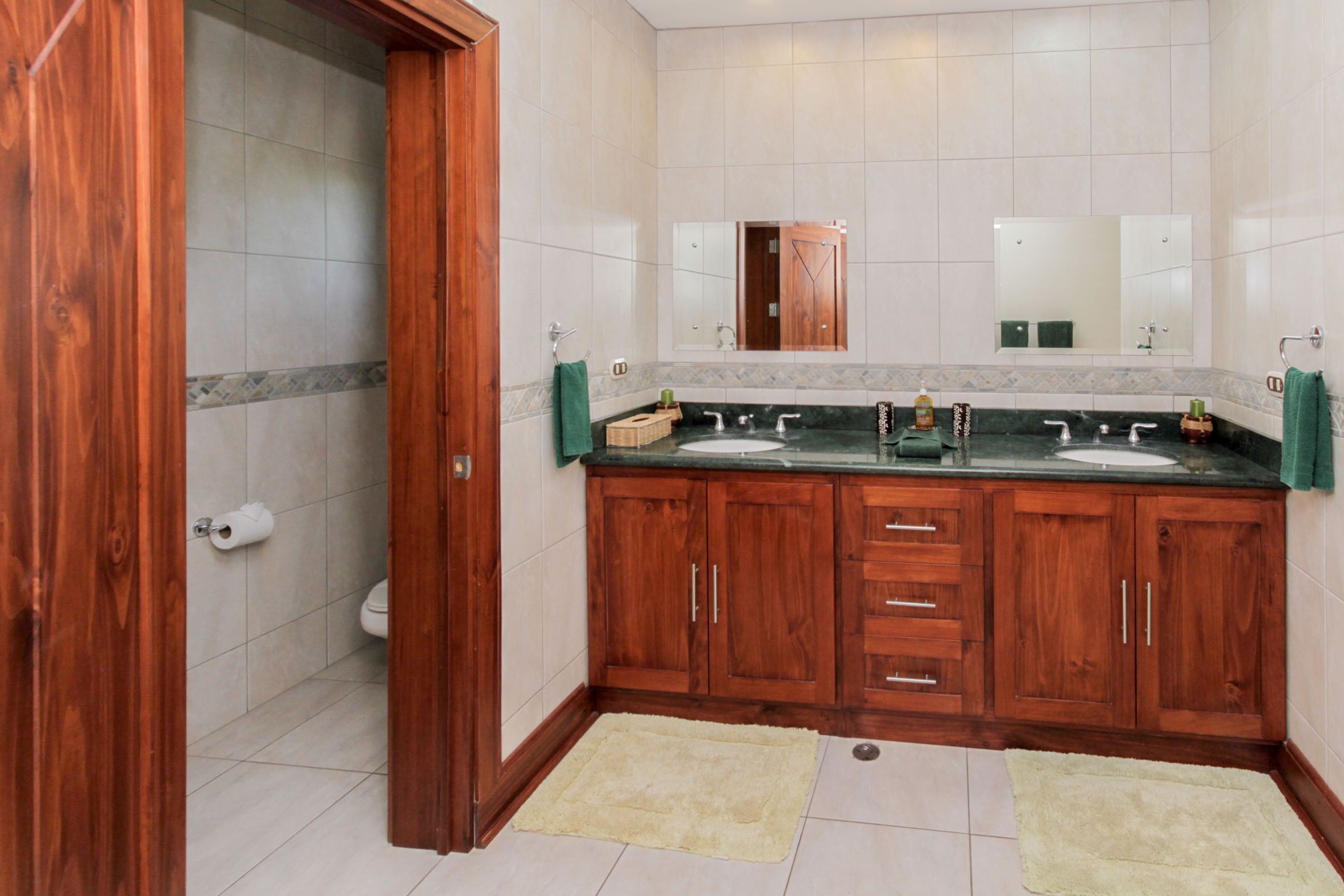 Un baño con dos lavamanos, armarios de madera, un espejo y un inodoro.