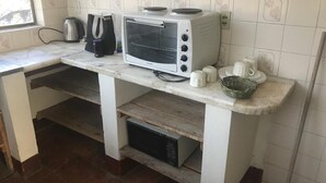 Una cocina con encimera blanca, microondas integrado, horno tostador blanco y hervidor.