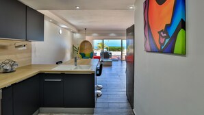 A modern kitchen with a wooden countertop, black cabinets, and a view to the outside. - ZEN Apartment T2 "Waterfront" Baie Nettle (BAIE NETTLE)