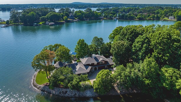Une propriété au bord du lac, avec une grande maison entourée d’arbres et une jetée.