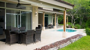 Un espacio al aire libre techado con piscina, mesa y sillas.