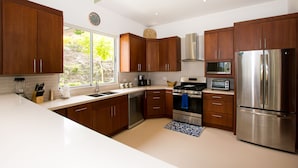 Una cocina moderna con armarios de madera, electrodomésticos de acero inoxidable y un amplio ventanal.