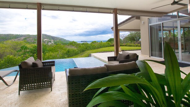 Un moderno espacio lounge al aire libre con piscina, asientos y vistas del paisaje.