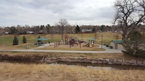 A playground with various play structures, a covered seating area, and a small shed.