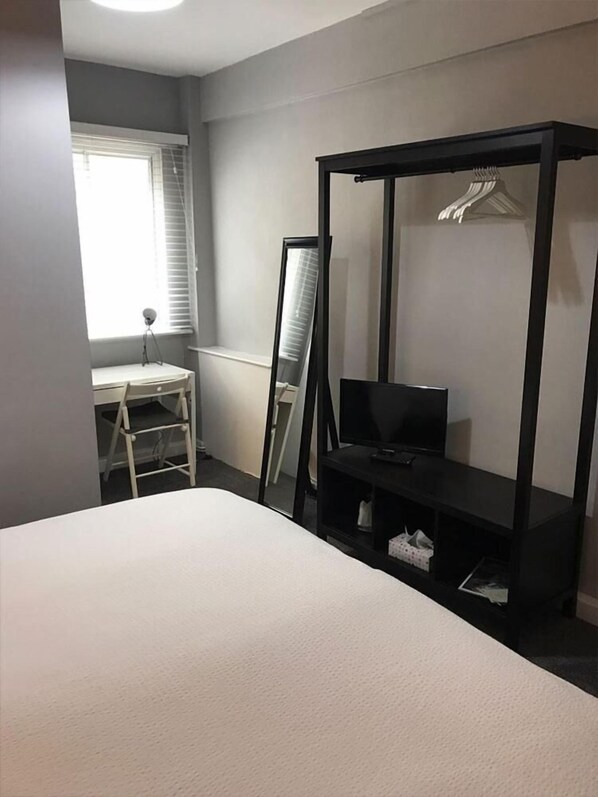 A bedroom with a bed, a desk, a chair, a TV, and a wardrobe. - The Waverley Hotel (Whitehaven)
