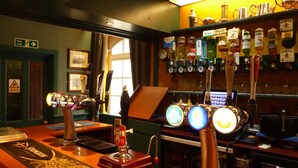 A bar area with multiple beer taps, a cash register, and a bottle of third beer. - The Waverley Hotel (Whitehaven)