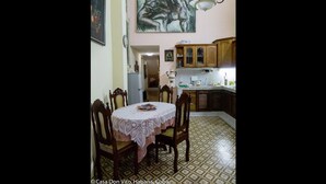 Un coin repas avec une table ronde et des chaises, une cuisine avec des meubles en bois et un grand tableau abstrait accroché au mur.