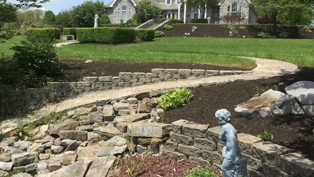 Un sendero de piedra que conduce a una casa, con una estatua al frente.