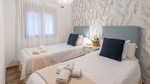 A hotel room with two beds, each with a white bedspread and matching pillows, and a small bedside table with a lamp and a plant. - Villa Las Gayumbas Villanueva de la Concepción by Ruralidays (Málaga)