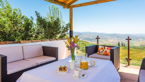 A terrace with a white table set for breakfast, wicker furniture, and a view of the countryside. - Villa Las Gayumbas Villanueva de la Concepción by Ruralidays (Málaga)