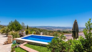 A rectangular swimming pool with a clear blue pool, surrounded by a stone wall, and a view of distant hills. - Villa Las Gayumbas Villanueva de la Concepción by Ruralidays (Málaga)