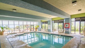 An indoor swimming pool with clear glass walls, a lifeguard sign, and a view of the outdoors. - 1101 Oceanfront End Unit Myrtle Beach HVAC UV SNAITIZER Lots of light and incredible views!! (Myrtle Beach)