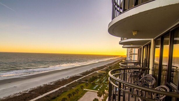 A balcony with a view of the beach and ocean during sunset. - 1101 Oceanfront End Unit Myrtle Beach HVAC UV SNAITIZER Lots of light and incredible views!! (Myrtle Beach)