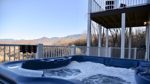 Ein Whirlpool mit Bergblick, eine Holzterrasse und ein überdachter Bereich mit Geländer.
