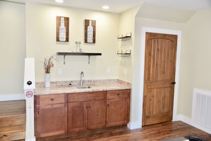 A kitchen with wooden cabinets, a marble countertop, and a wooden door.