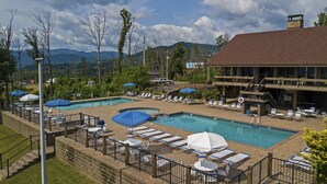 Ein Resort mit Poolbereich, Liegestühlen und Bergblick.