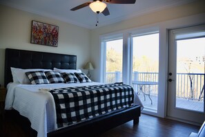 Ein Schlafzimmer mit einem großen Bett, einem Deckenventilator und einem Balkon mit Tisch und Stühlen.