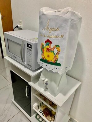 Kitchen features a microwave, refrigerator, and cabinet with a water dispenser.