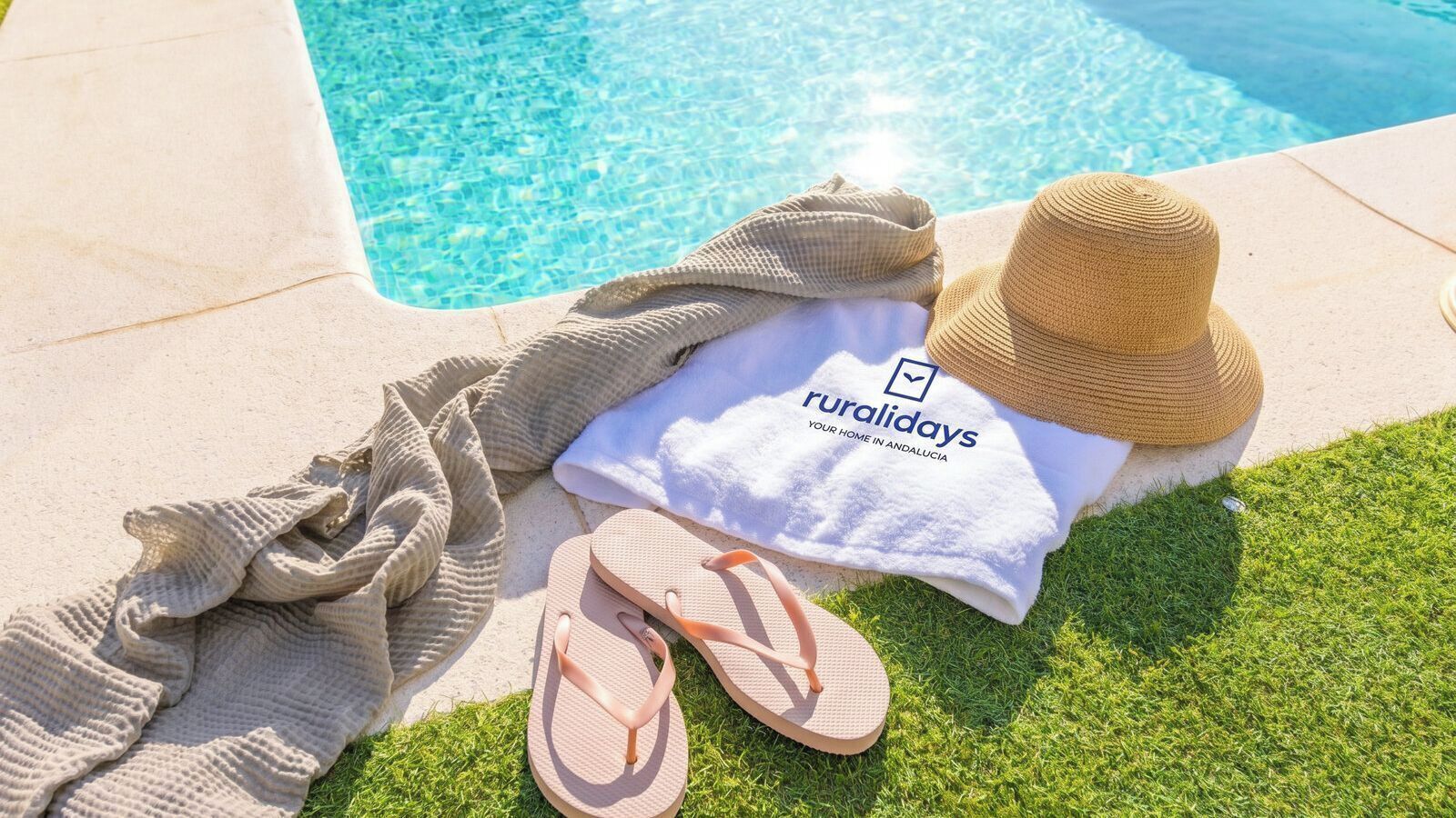 Area piscina con asciugamano, cappello, infradito e asciugamano con marchio.