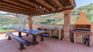 Une terrasse extérieure avec un barbecue en pierre, des tables et des bancs en bois.
