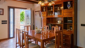 Un coin repas avec une table et des chaises en bois, un meuble encastré doté de portes en verre et une vue sur l’extérieur grâce à une porte coulissante.