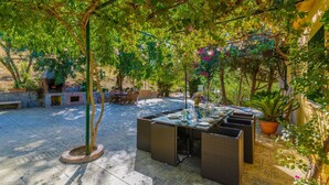 An outdoor patio with a table set for dining, surrounded by potted plants and a brick oven. - El Molinillo Casabermeja by Ruralidays (Málaga)