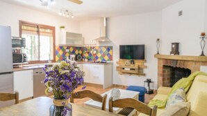 A modern kitchen with a dining area, a TV, and a fireplace. - El Molinillo Casabermeja by Ruralidays (Málaga)