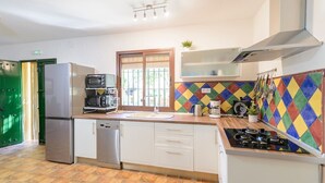 A kitchen with a dishwasher, a stove, a microwave, and a coffee maker. - El Molinillo Casabermeja by Ruralidays (Málaga)
