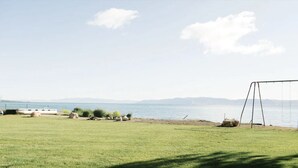 A grassy field with a swing set and a boat docked by the water. - Spinnaker Point Dr - Unbeatable BEACH FRONT property for a large group! (Garden City)