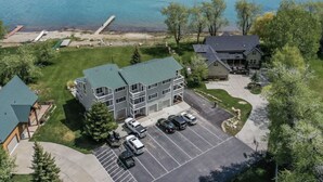 An aerial view of a residential area with a large building, a parking lot, and a body of water in the background. - Spinnaker Point Dr - Unbeatable BEACH FRONT property for a large group! (Garden City)