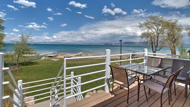 A deck with outdoor furniture overlooking a beach and a grassy area with playground equipment. - Spinnaker Point Dr - Unbeatable BEACH FRONT property for a large group! (Garden City)