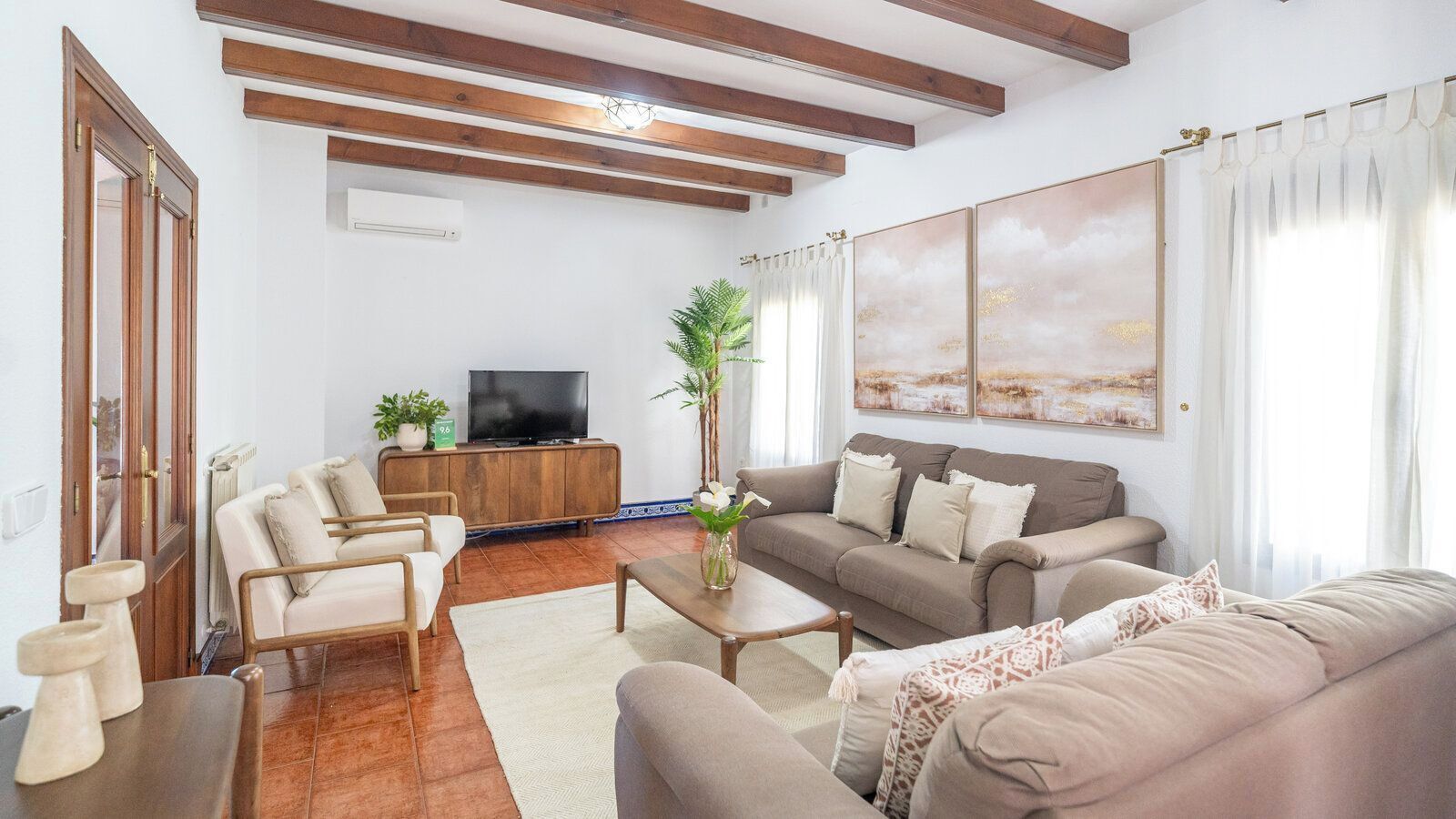 A living room with a sofa set, a coffee table, a TV, and a plant.