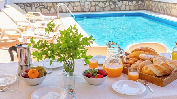 Une table de petit-déjeuner installée avec une piscine en arrière-plan.