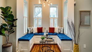 A cozy seating area with a built-in bench, a small table with a vase and books, and a potted plant. - Stunning Home on Capitol Hill (Washington)