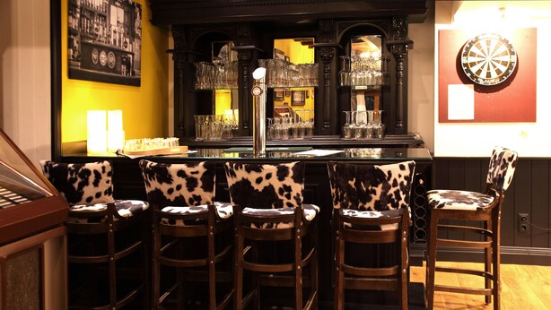 A bar area with a counter, bar stools, and a dartboard. - Chalet Mirandum Rustiko (Vandans)