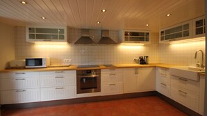 A kitchen with white cabinets, a microwave, an oven, and a sink. - Chalet Mirandum Rustiko (Vandans)