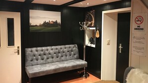 A modern interior with a grey sofa, a mirror, a chandelier, and a 'No Smoking' sign. - Chalet Mirandum Rustiko (Vandans)