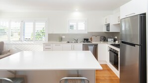 A modern kitchen with white cabinets, stainless steel appliances, and a large island.
