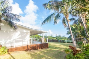 Guests can enjoy a deck with a railing, surrounded by lush greenery and a palm tree.
