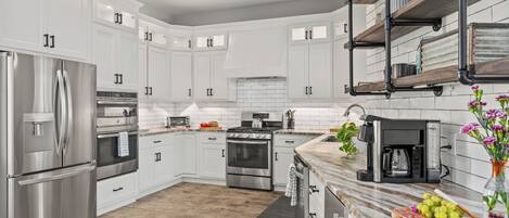 Una cocina moderna con armarios blancos, electrodomésticos de acero inoxidable y encimera de mármol.