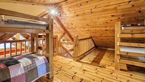 A wooden cabin interior with a bunk bed, a quilted blanket, and a wooden staircase. - Ski Lodge Mtn Retreat w/ Fire Pit, Deck & Views! (Starksboro)