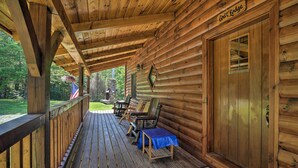 A wooden cabin with a covered porch, a sign reading "Cruz Lodge," and a view of a grassy area with a flag. - Ski Lodge Mtn Retreat w/ Fire Pit, Deck & Views! (Starksboro)