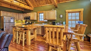 A rustic kitchen with wooden cabinets, a large island with stools, and a wooden ceiling. - Ski Lodge Mtn Retreat w/ Fire Pit, Deck & Views! (Starksboro)