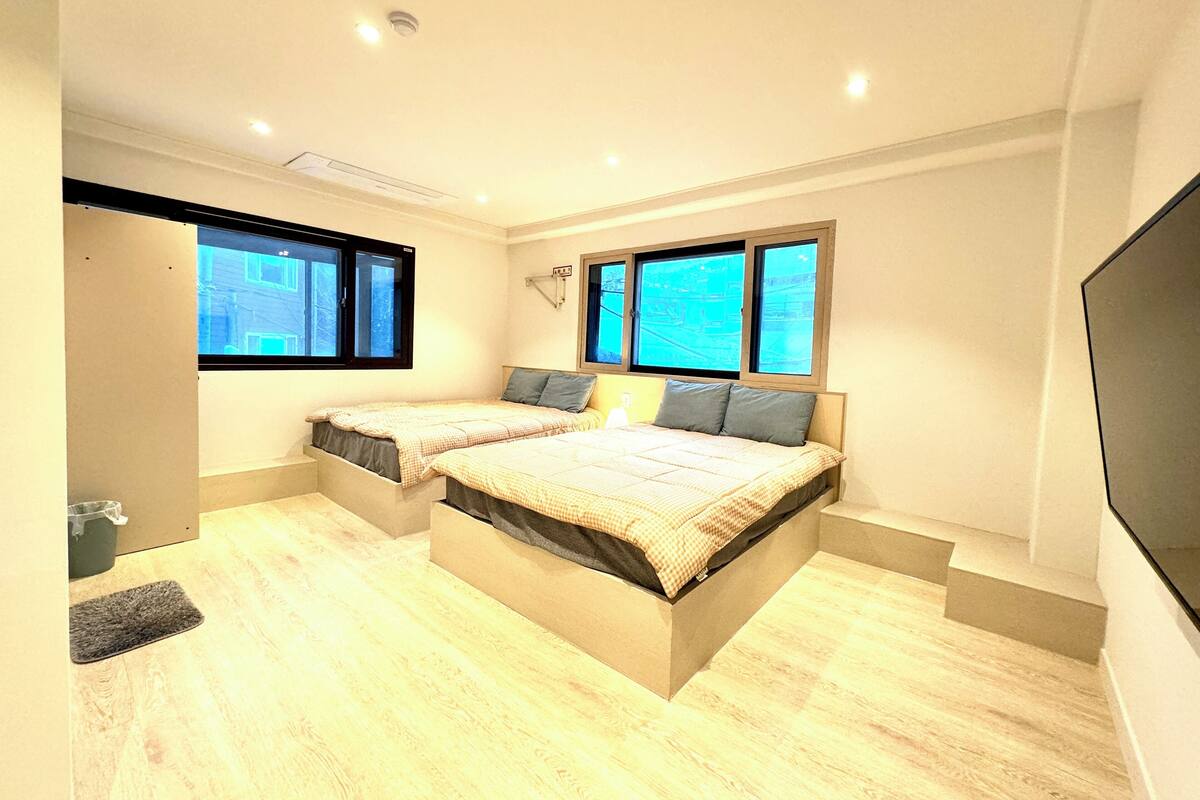 Un dormitorio con dos camas, televisión y ventanas con vistas.