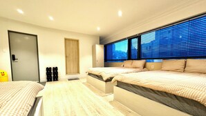 A modern hotel room with two beds, a large window with blinds, a door, and a small window with a view. - Namsan Forest Myeongdong Station (Seoul)