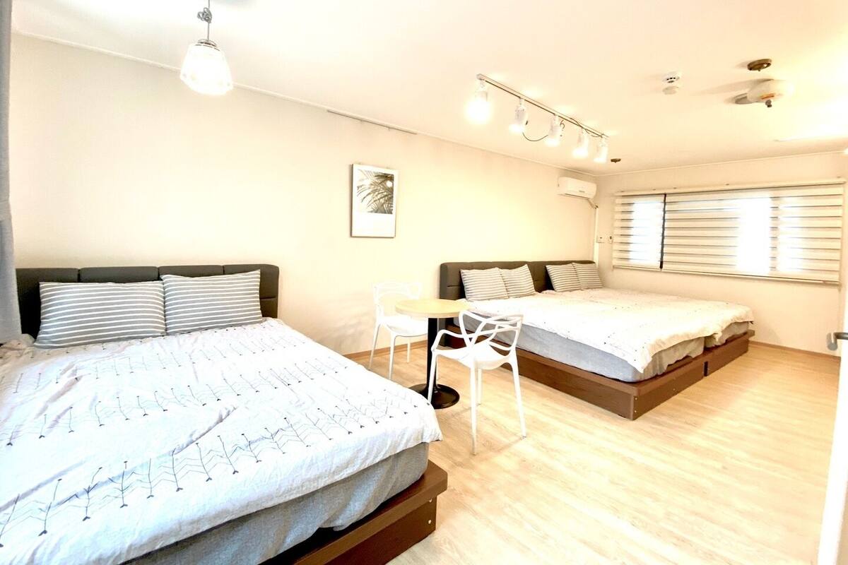 Un dormitorio moderno con dos camas, una mesita y una silla.