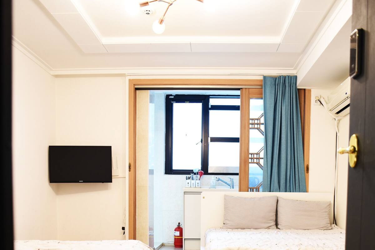 Un dormitorio con cama, televisor, ventilador de techo y vistas al exterior.