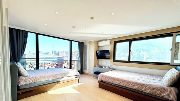 A modern bedroom with two beds, a TV, and a balcony with a city view. - Namsan Forest Myeongdong Station (Seoul)